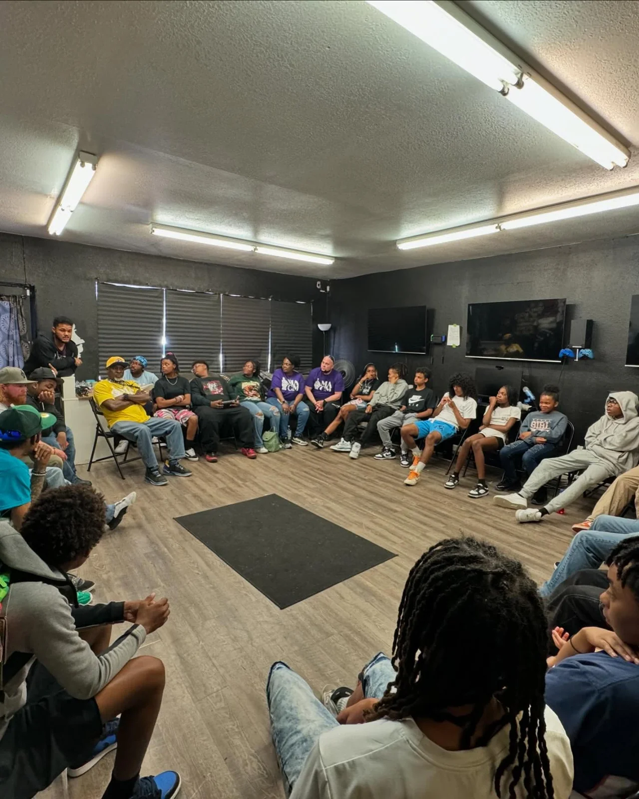 Young people and adults seated in a circle inside a MACM room