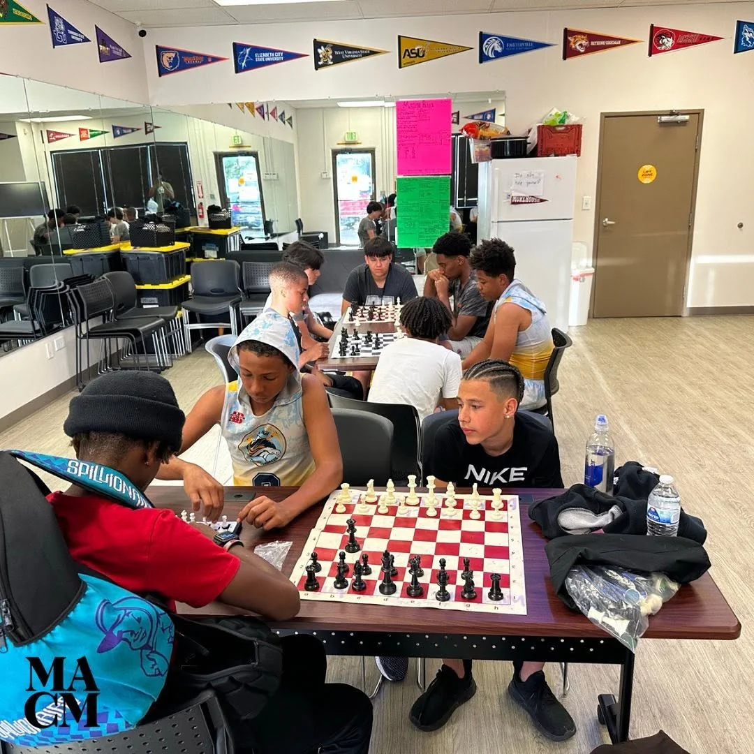 A group of youth playing chess together in a MACM room