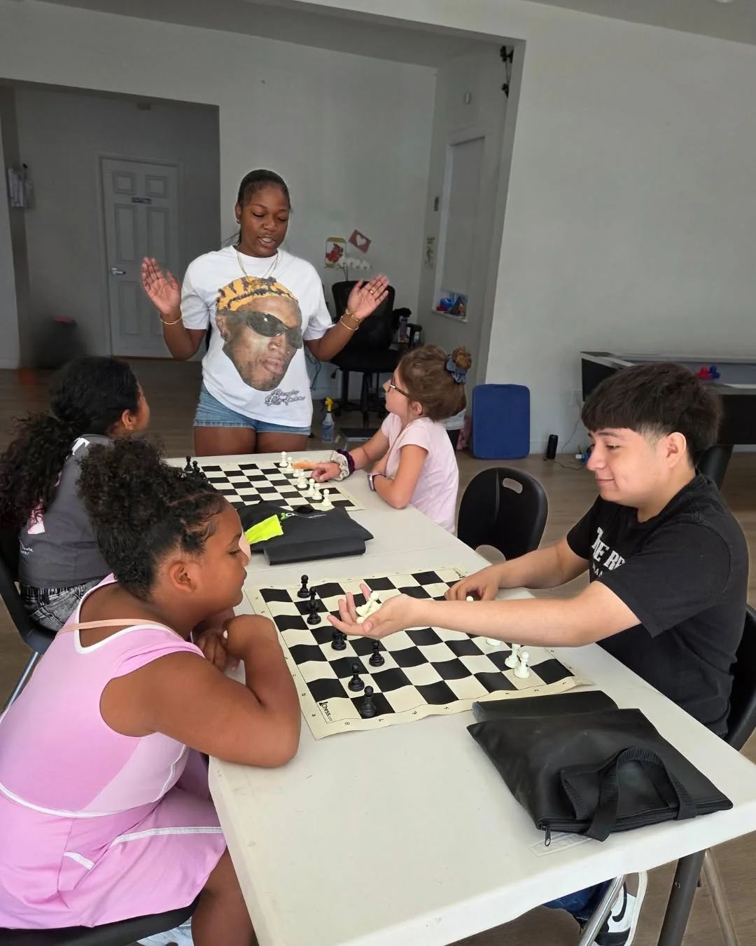 A young woman facilitating a chess and discussion session with children
