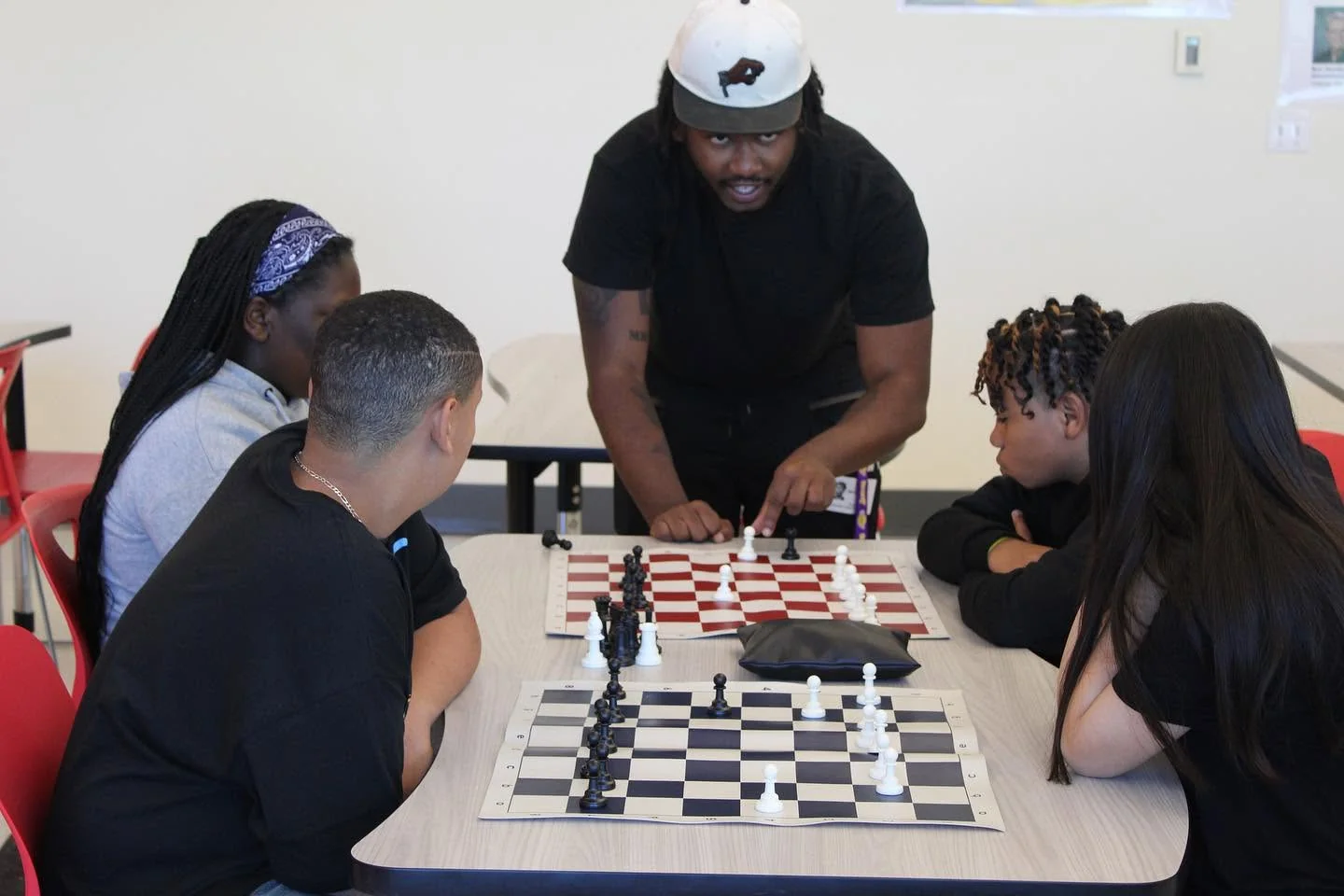 A staff member coaching youth around a chessboard