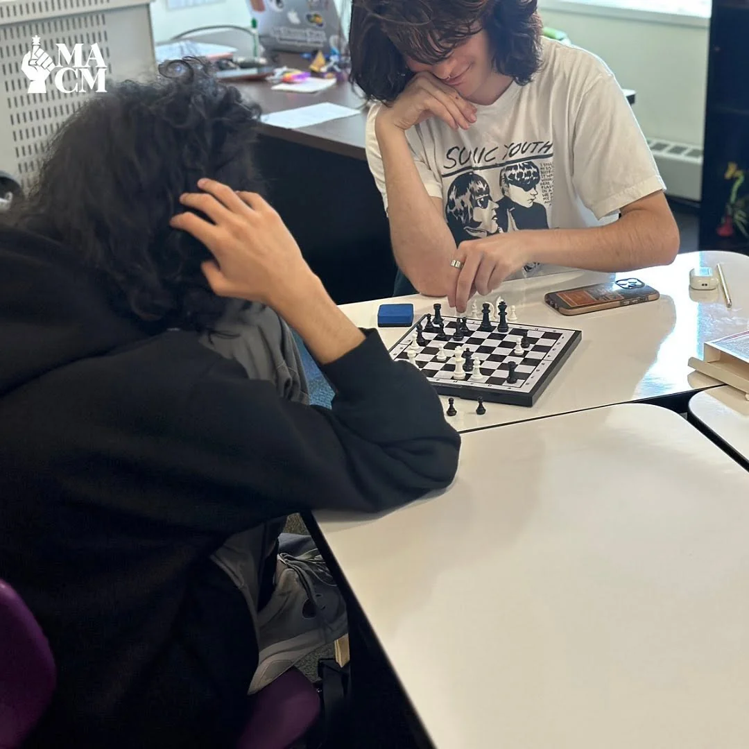 Two teens studying a chessboard together